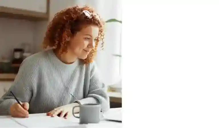 girl taking note smiling at a laptop