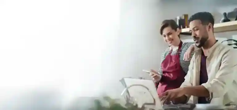 man and woman working on laptop smiling